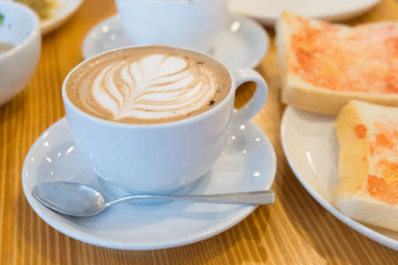 Fresh coffee with heart love foam in with cup and toastの写真素材
