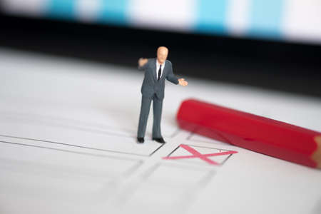 Miniature people of a politician standing on election ballot with red pen. Election debates or press conference conceptの写真素材