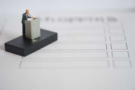 Miniature people of a politician speaking with microphone on the podium. Election debates or press conference conceptの写真素材