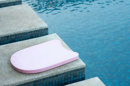 Pink foam board for the teaching of swimming beside swimming pool