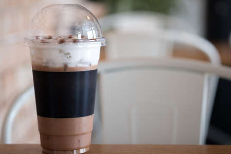 Iced chocolate cocoa glass and straw on table in coffee shop