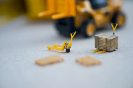 Miniature yellow toy forklift and miniature pallet truck. Concept of international freight transportの写真素材