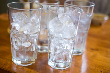 Ice in a clear tall glass in wooden table