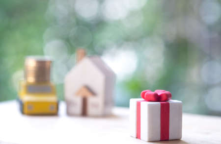 Gift box with ribbon with home and car background for surprise. Surprise and successful conceptの写真素材