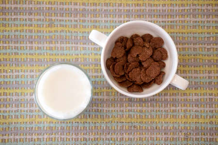 Chocolate corn flakes in clay bowl served with fresh milk
