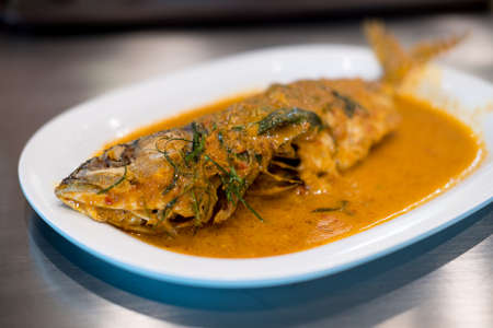 Fried fish with red curry paste on white dish, Thai food