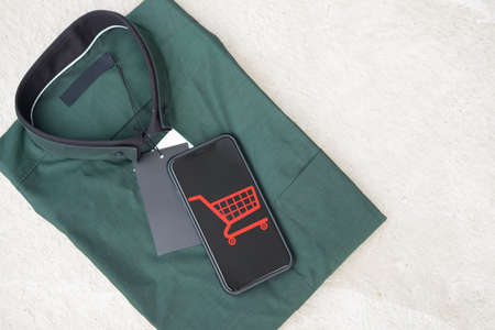 Smart mobile phone with online shopping store put on man green shirt. Business internet shop online...