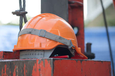 protective orange helmet lies on a black board, used in construction for safety and head protection, closeupの写真素材