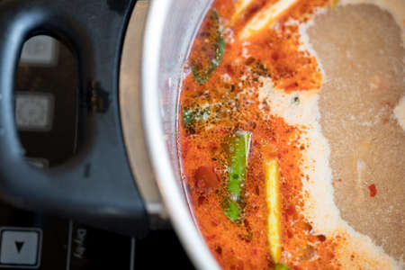 Red hot and sour soup in a iron pot. Spicy tom yum goong Thai style soupの写真素材