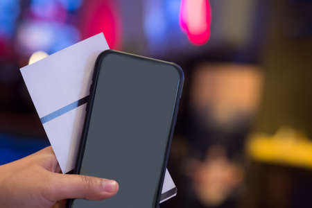 Hand show paper tickets and show reserved seating on mobile smartphone. Online booking and payment conceptの写真素材