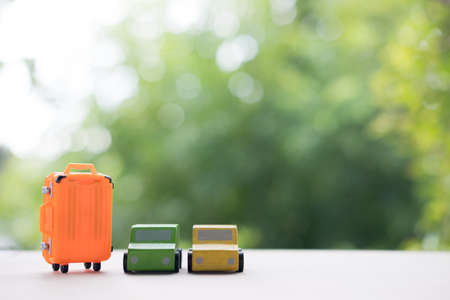 Miniature toy car and miniature orange suitcases on nature background. Concept of travel or travel insuranceの写真素材