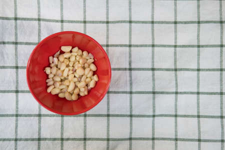 Fresh peeled organic garlic cloves in a small red bowlの写真素材