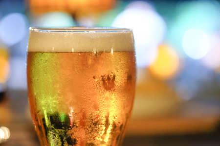 A glass of beer with colorful light in night pubの写真素材
