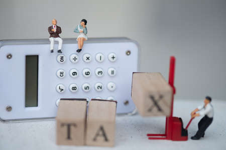 Miniature people businessman sit on calculator for think pay annual income (TAX)  yearの写真素材