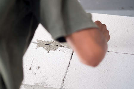 Real construction worker bricklaying the wall indoors. Home renovation concept.