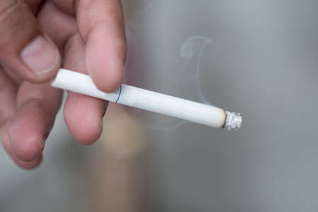 Cigarette smoke burning on hand man smoking (Cigarette in hand)の写真素材