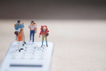 Miniature people backpacker standing on white calculator for calculate money and time to travel. Concept of travel planning and save costの写真素材