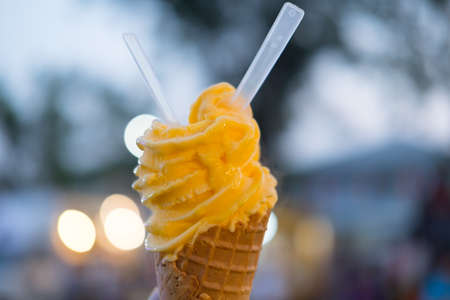 Hand holding orange ice cream cone. Orange ice cream made by passion fruitの写真素材