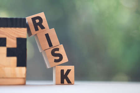 Cube wooden block with alphabet building the word RISK. Unpredictable situation concept