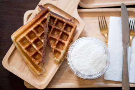 Waffles with ham and cheese served with ice drink on wood tray, selective focus milk drinkの写真素材