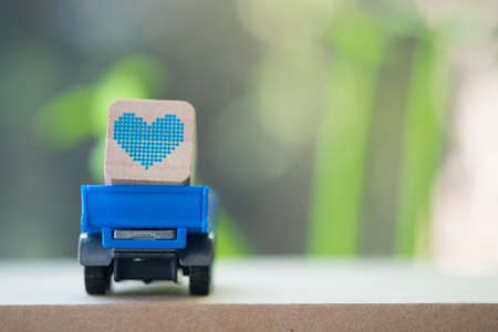 Blue toy car carrying blue heart on the table for Valentines day background