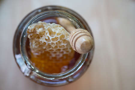 Fresh golden honey sweet with honeycomb and wooden honey dripping in glass jarの写真素材