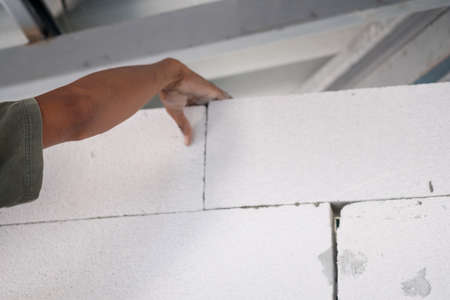 Real construction worker bricklaying the wall indoors. Home renovation concept.