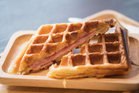 Grilled waffles with bacon on wooden tray, close up