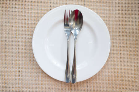 White color plate and utensil (spoon and fork) on table in restaurant. food concept.