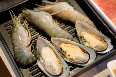 Fresh raw shrimp and mussel on black tray ready to cookの写真素材