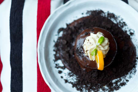 Warm dessert chocolate cake lava served on plate decoration with fresh orange slice and whipping...