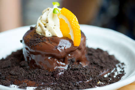 Fondant chocolate cake with orange slice and whip cream, close up