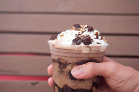 A delicious chocolate frappe in plastic cup in hand