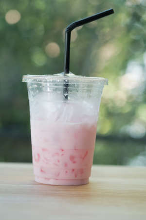 Iced pink fresh milk in plastic cup and straw after drink finishedの写真素材