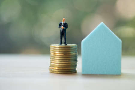 Miniature people standing on gold coins stack with home. Retirement planning, Emergency plan, Life...