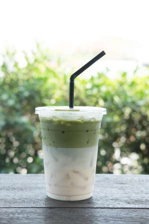 Iced matcha or iced matcha green tea on wood table with blur nature background
