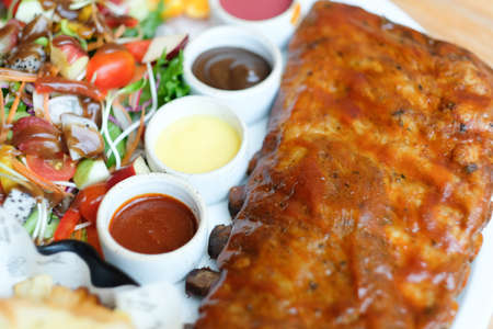 Roasted pork ribs with barbecue sauce and fruit salad served with three salad dressing
