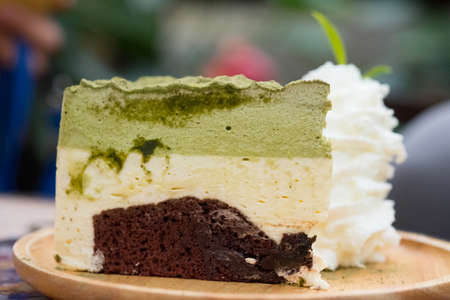 Sweet matcha green tea cake and wipping cream served on wood dish.の写真素材