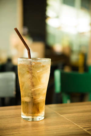 Glass of fresh summer ice tea drink with ice on wood table