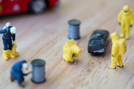 Miniature people: Figure of firefighter team in hazmat suit standing next to car. Crime scene...