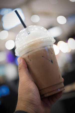 Iced coffee in a plastic glass with cream poured overの写真素材