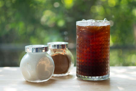 Iced black coffee in long glass with sugar and brown sugar in glass bottle for add sweet in drinkの写真素材