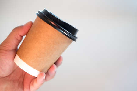 Brown paper cups and blank caps in hand, Concept of branding identity and advertising