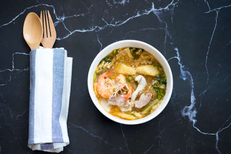 Seafood and pork sukiyaki in white bowl on marble black background