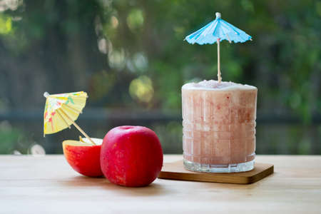 Apple fruit smoothie ice drink on wood table with nature background, concept of healthy and summer drinkの写真素材