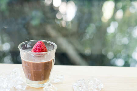 Glass of dark chocolate with fresh strawberry served with ice