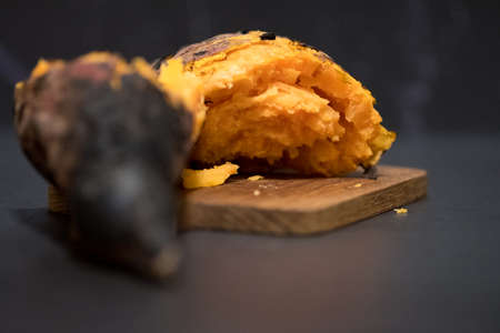 Thai grill sweet potato served on wooden tray with black background. Selective focus