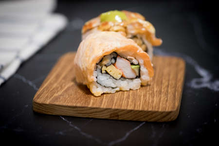 Sushi rolls with salmon on wooden plate
