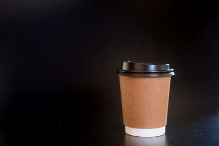 Disposable brown paper cups for coffee on a black backgroundの写真素材
