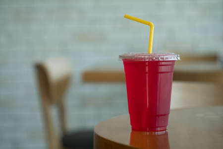 Mixed red syrup and soda with ice cubes on wood tableの写真素材